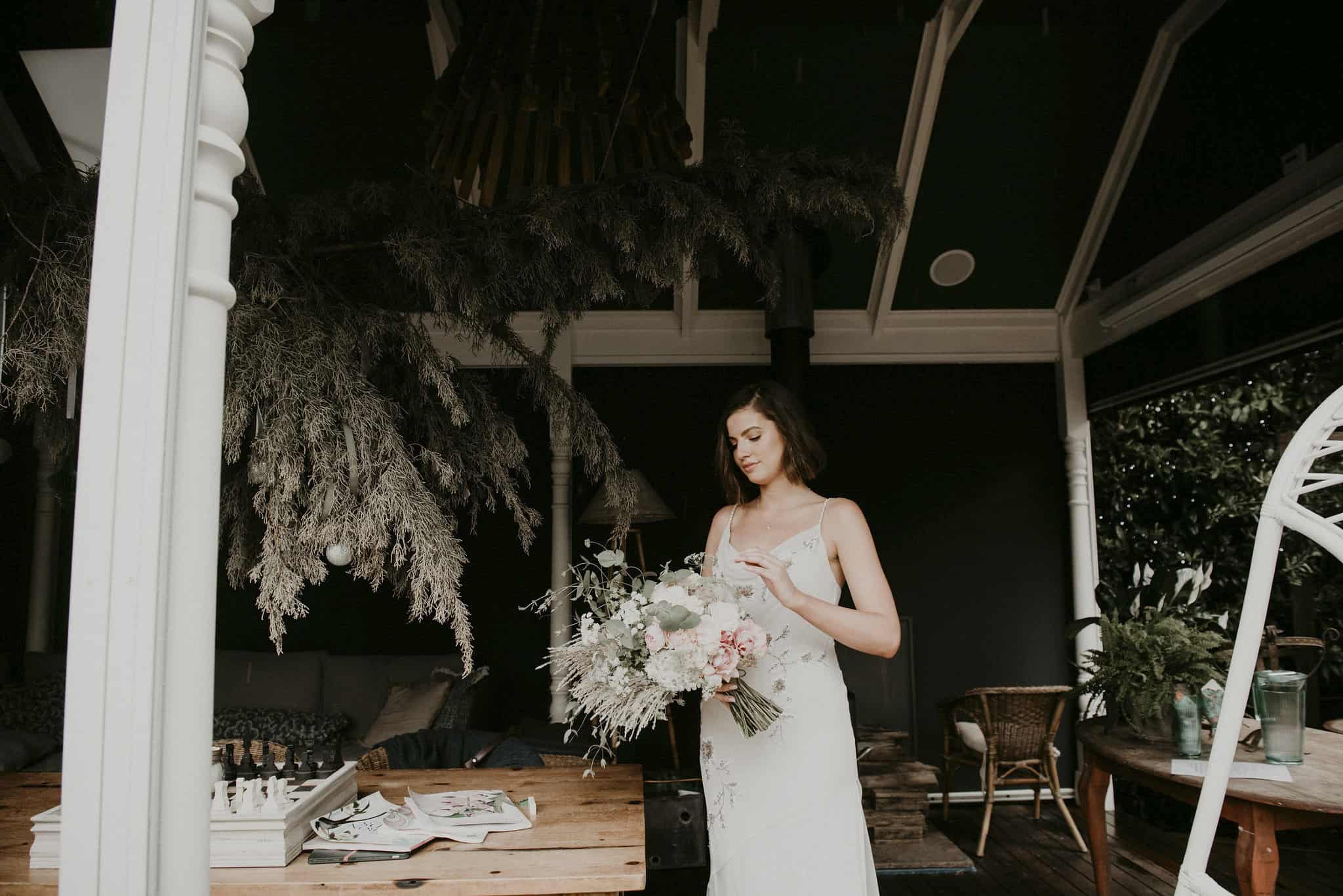 Bride looks down at her floral bouquet under patio taking a moment before the ceremony begins Lets Elope Melbourne Celebrant Photographer Elopement Package Victoria Sarah Matler Photography intimate elopement Acre of Roses Trentham Moody wedding