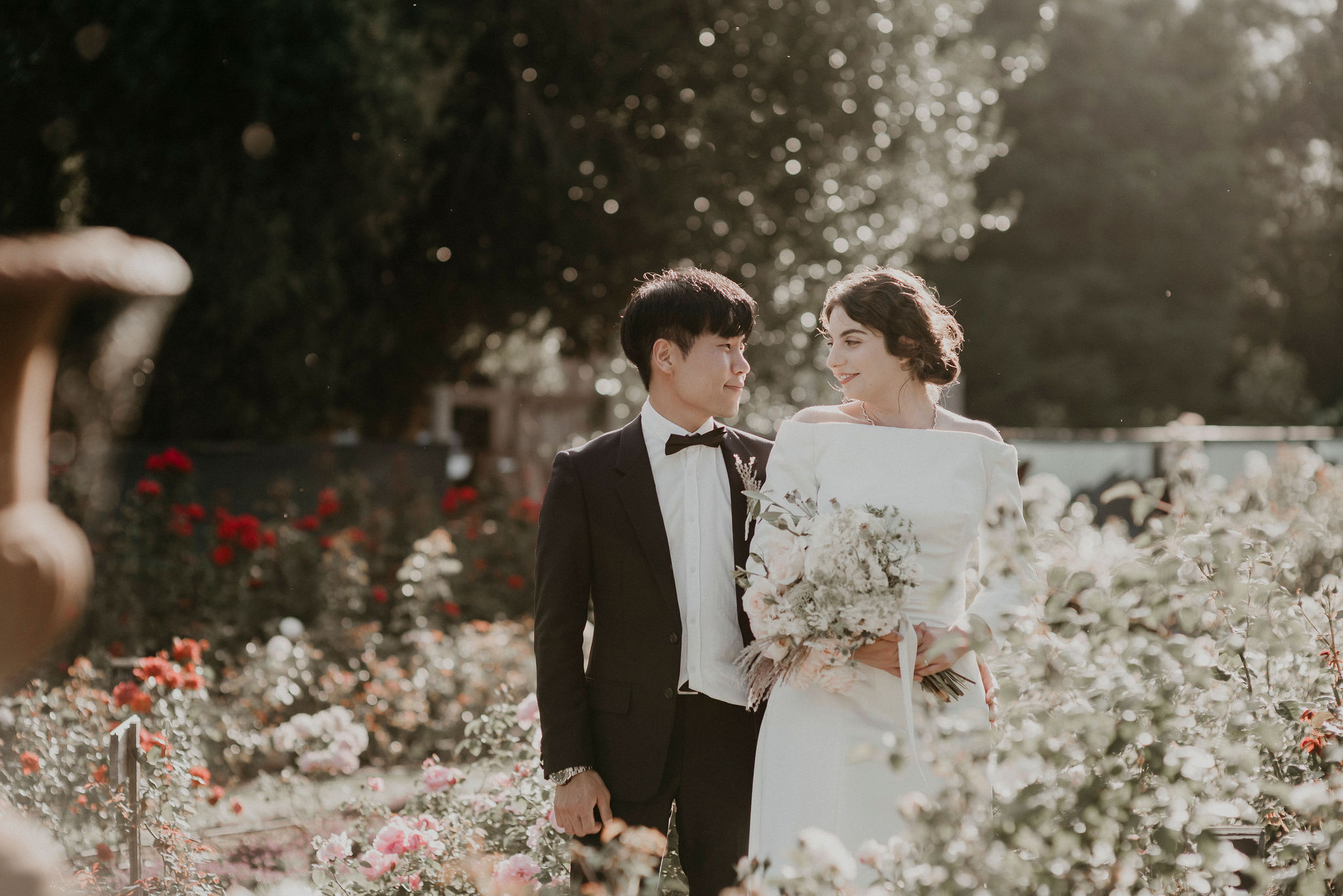 Bride and groom stand smiling at each other amongst the roses bathed in the afternoon light Let's Elope Melbourne Portfolio Celebrant Photographer Elopement Packages Victoria Sarah Matler Photography intimate weddings Acre of Roses Trentham romantic ceremony