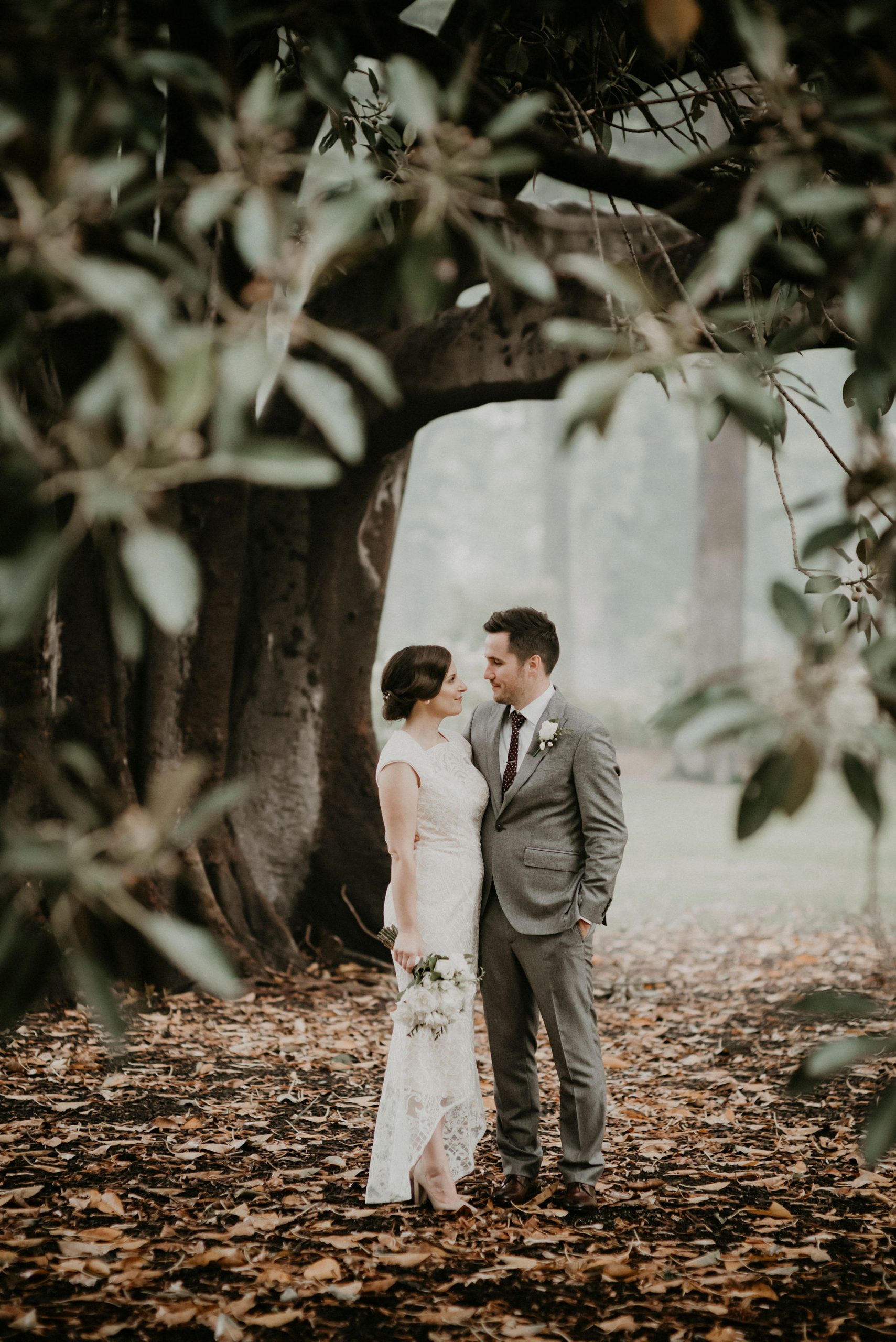 Couple stand in front of fig tree in the rain and fog Let's Elope Melbourne Portfolio Celebrant Photographer Elopement Package Victoria Sarah Matler Photography intimate wedding Fitzroy Gardens Fog Moody East Melbourne
